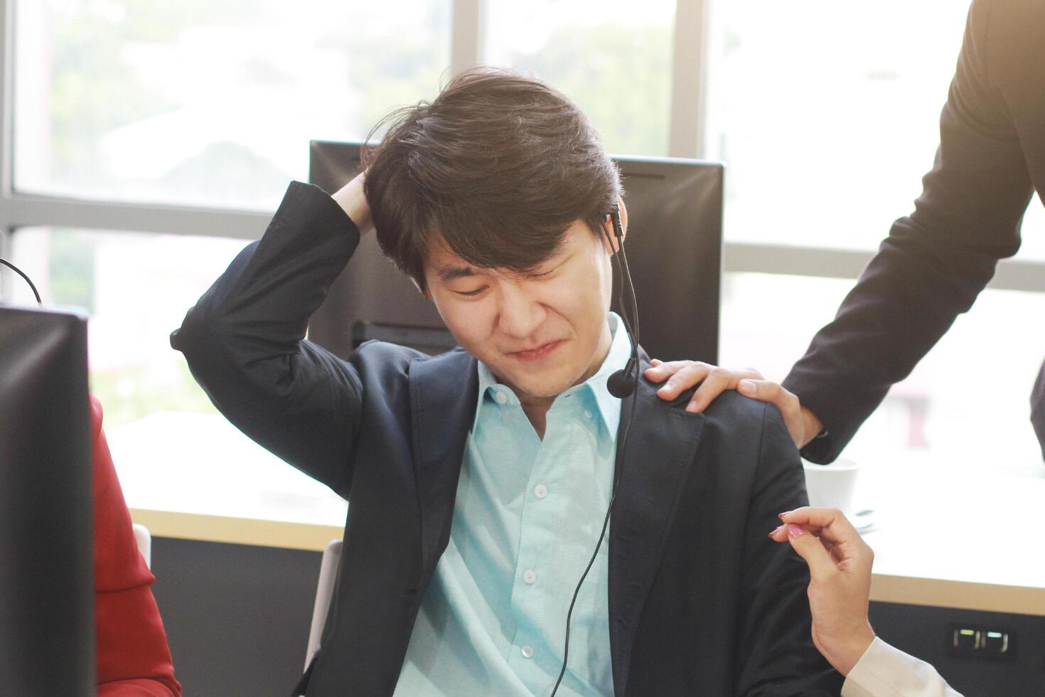 Call Center man and technical Support staff for receptionist phone operator serious and headach in work and teamwork encouraging Male employee. Asian customer support team. photo