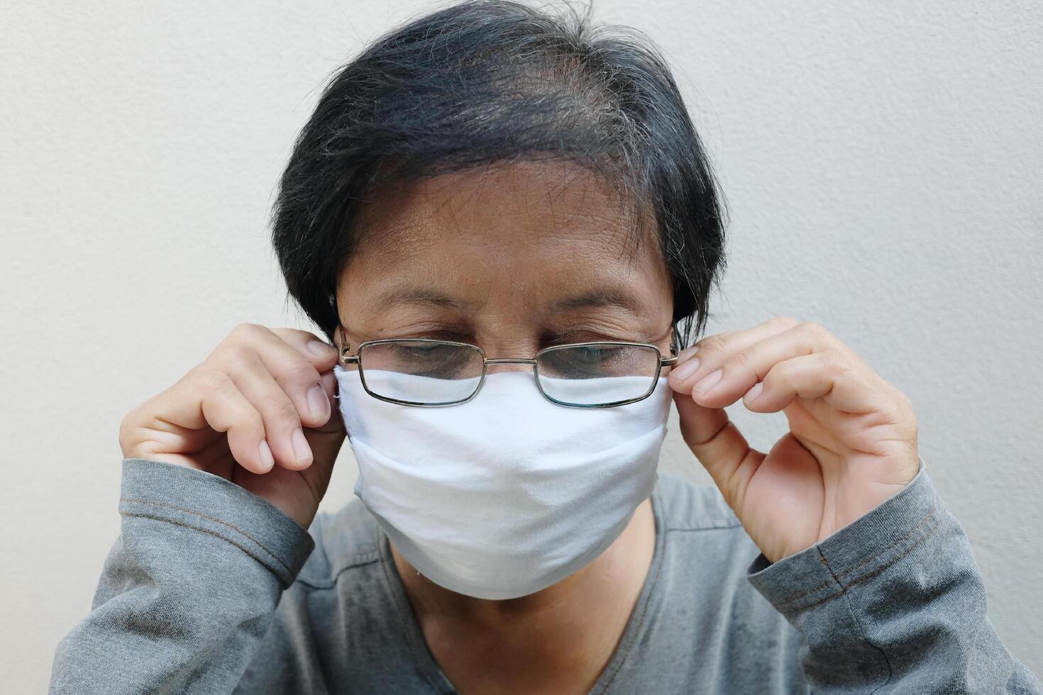Asian old woman wearing glasses and white cloth mask for prevent the Covid-19 or Corona virus in Thailand and protect for Air Pollution Value Pm 2.5. Health and medicine of elderly concept photo