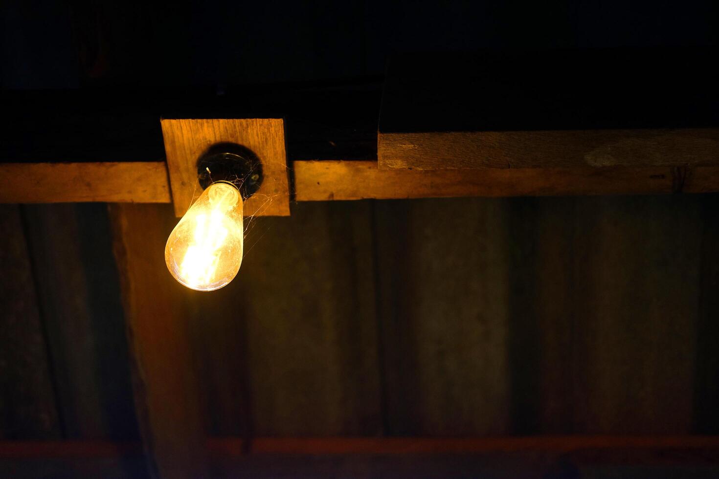 Light bulbs is hanging on wooden beam indoor of cafe and vintage house building photo