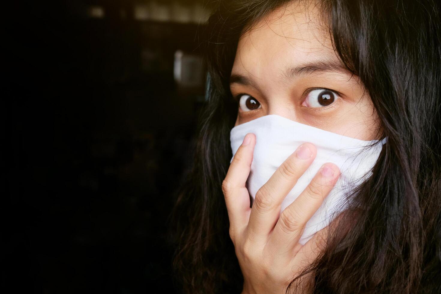 Asian Thai woman wearing a white cloth mask for prevent the Covid-19 or Corona virus in Thailand. She is serious and Coughing about Air Pollution Value Pm 2.5. Health and Respiratory system concept photo