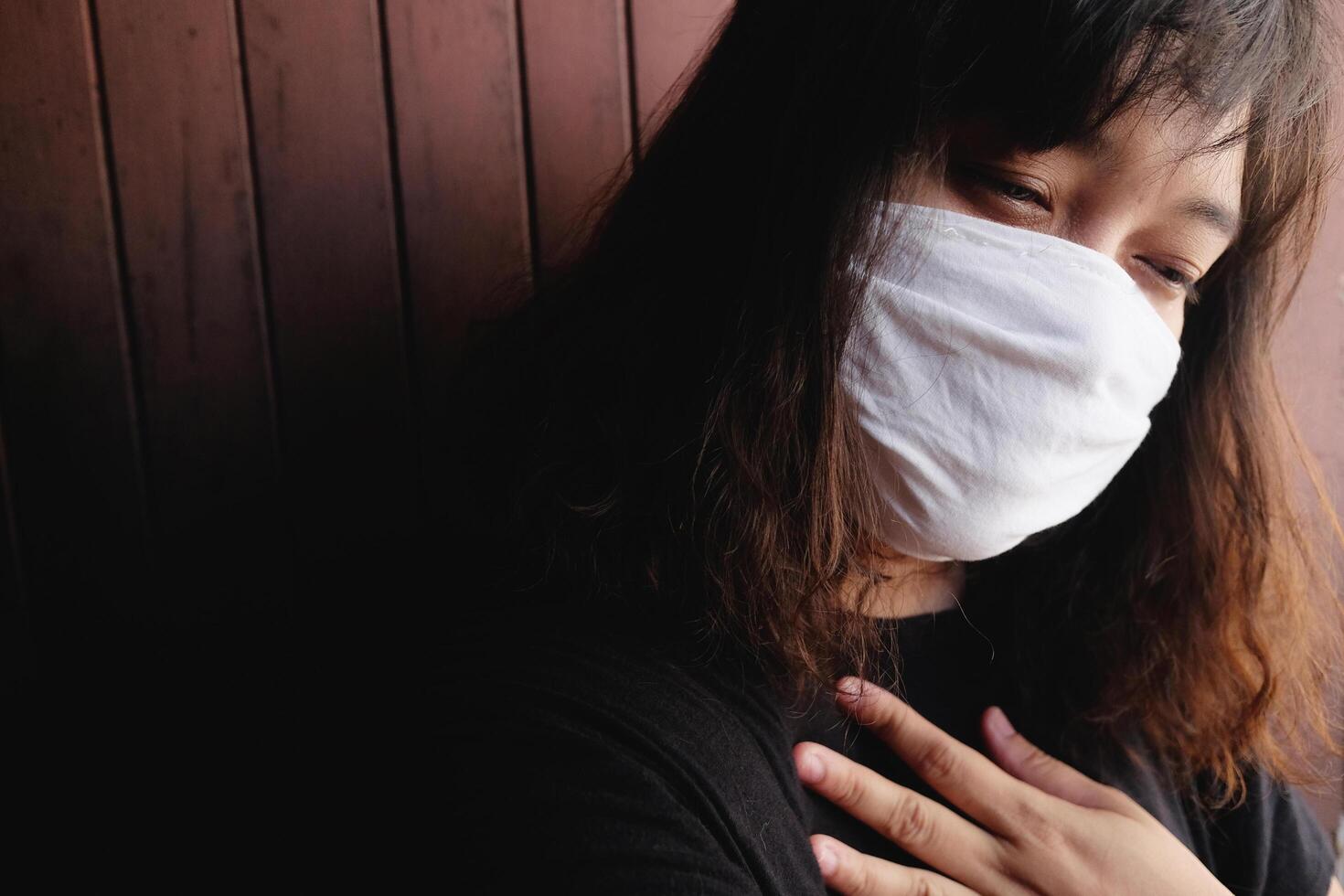 Asian Thai woman wearing a white cloth mask for prevent the Covid-19 or Corona virus and Air Pollution Value Pm 2.5 in Thailand. She is suffocating in Respiratory system. Health and illness concept photo