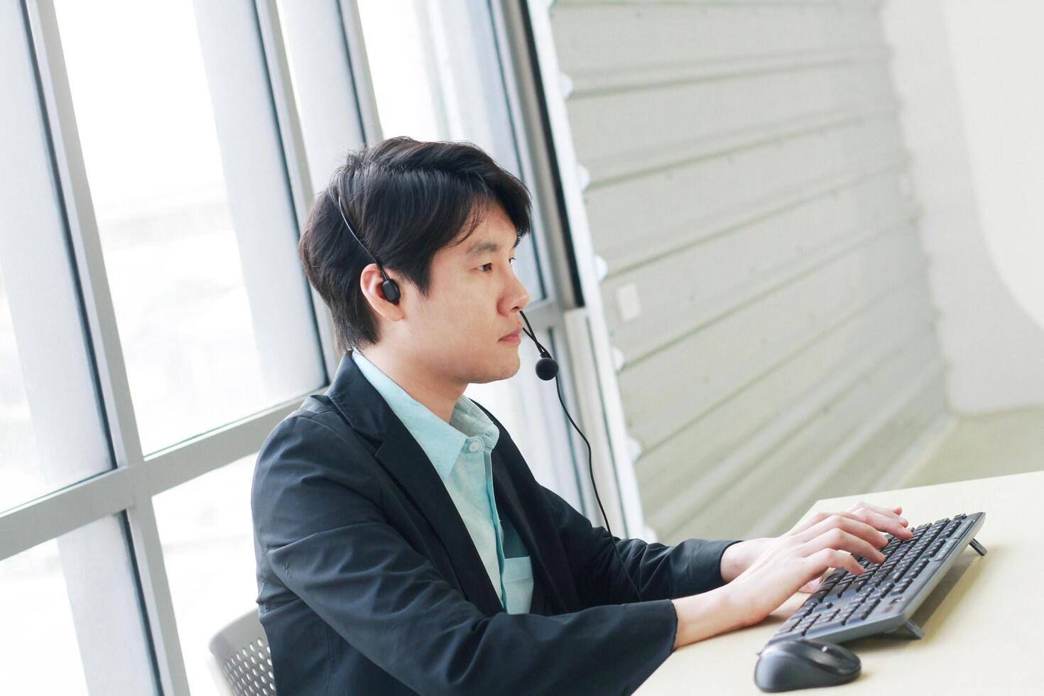 Businessman Call Center and technical Support staff with headset talking and serious with job. Asian customer support team. photo