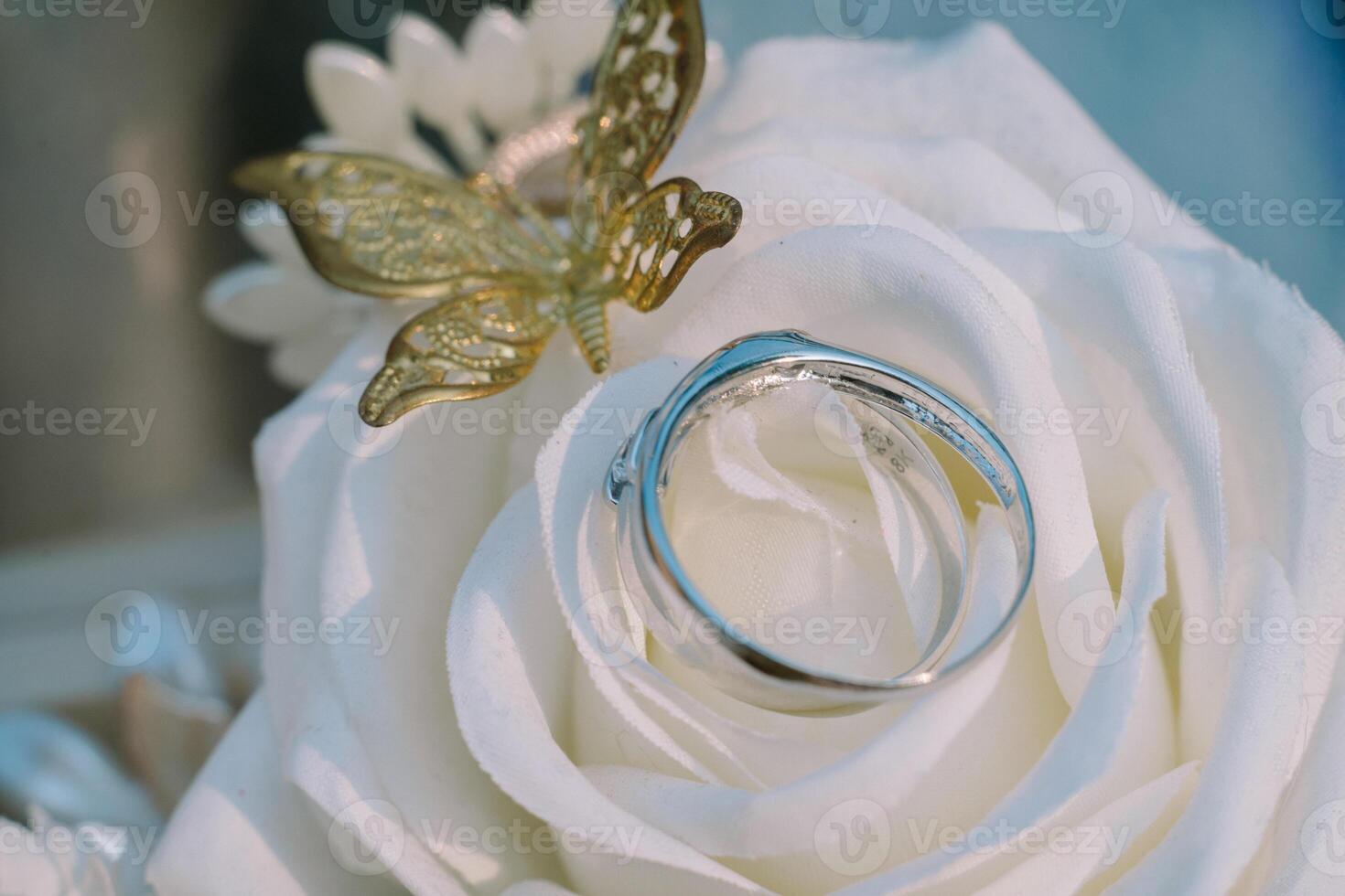 A wedding ring adorned with a delicate white rose and butterfly motif crafted from gold, symbolizing eternal love and the beauty of union. photo
