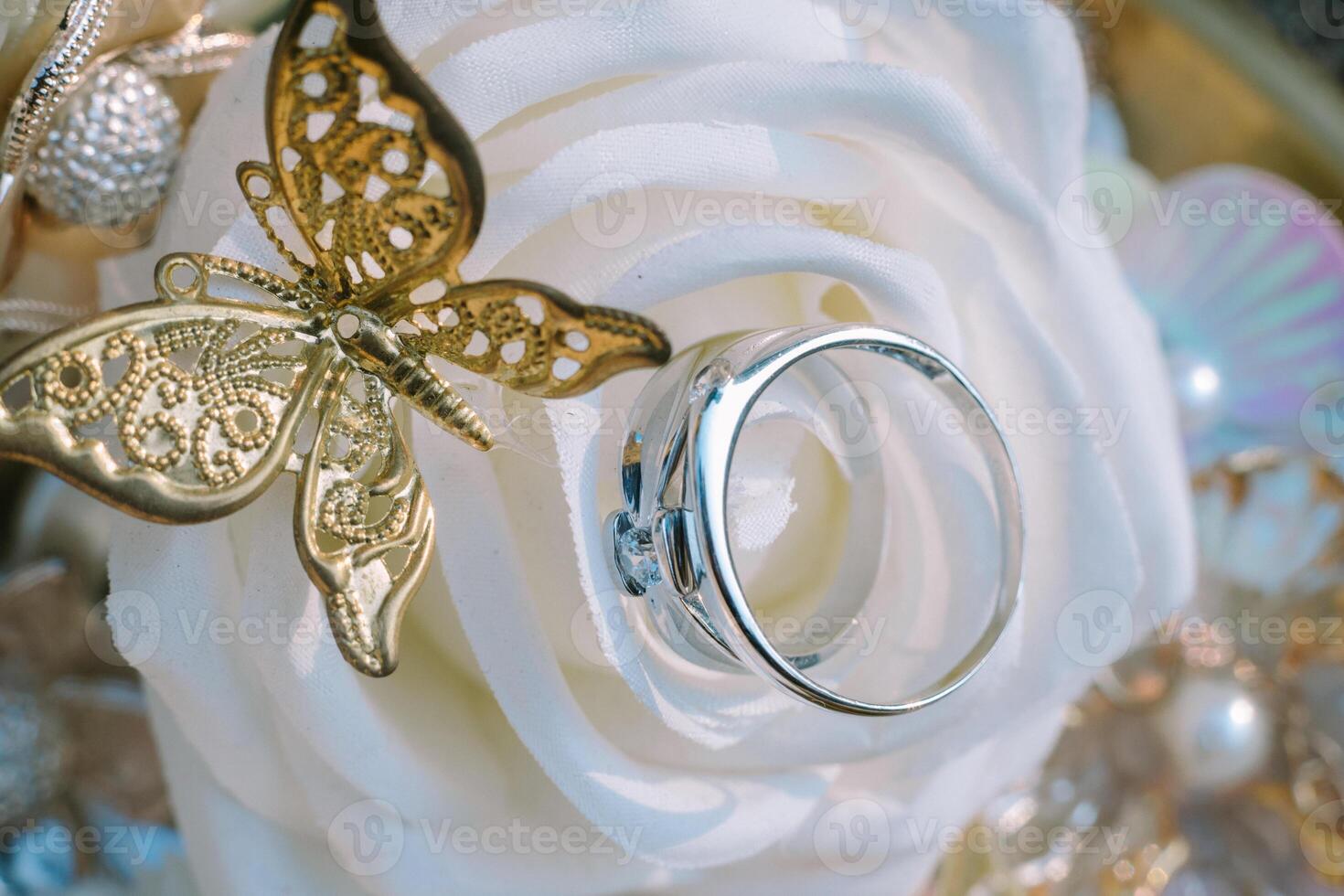 A wedding ring adorned with a delicate white rose and butterfly motif crafted from gold, symbolizing eternal love and the beauty of union. photo