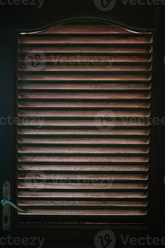 A wooden door featuring linear vents, blending functionality and rustic charm, perfect for enhancing ventilation and aesthetic appeal in any space. photo