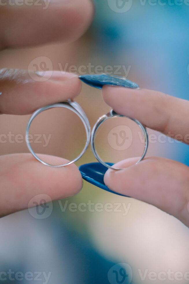 A wedding ring held between the fingers of a newlywed couple, symbolizing their eternal love and commitment. photo