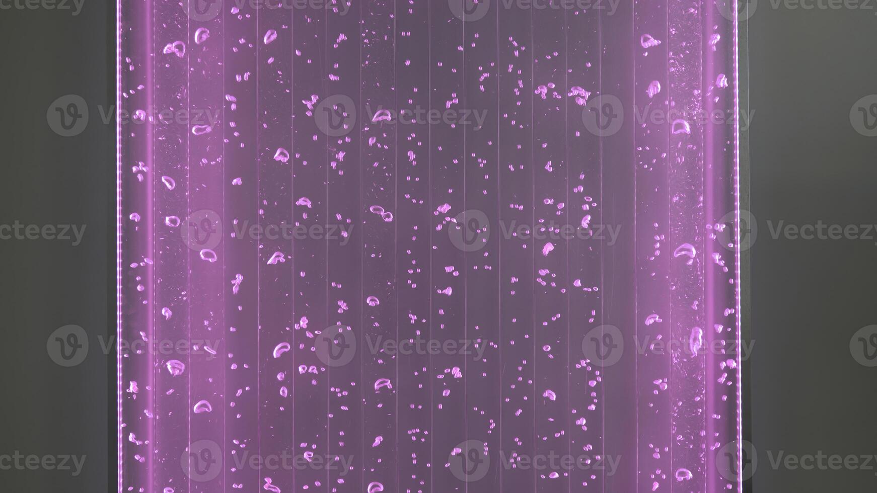 Luminous lamp with water and bubbles. Clip. Mesmerizing wall decor with glowing lamp and bubbles. Moving water bubbles in neon lamp on wall photo