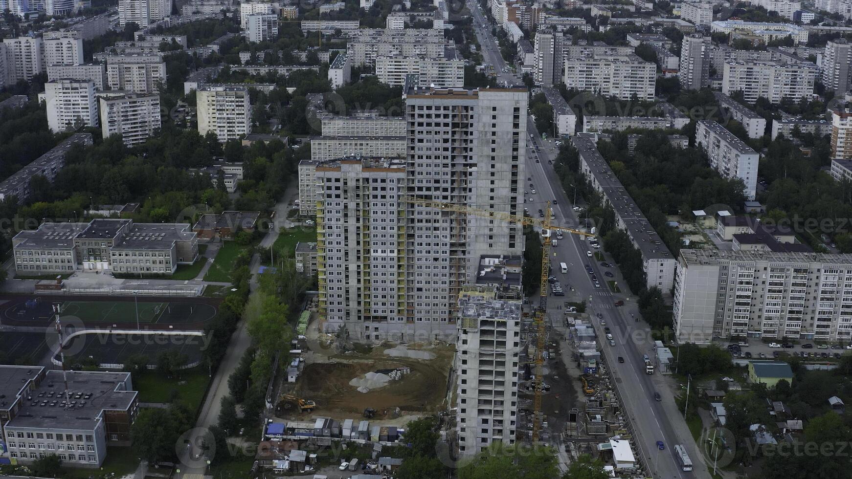 Top view of city with construction of high-rise building. Stock footage. Construction of multi-storey complex in residential area of modern city. Construction of high-rise building with crane on photo
