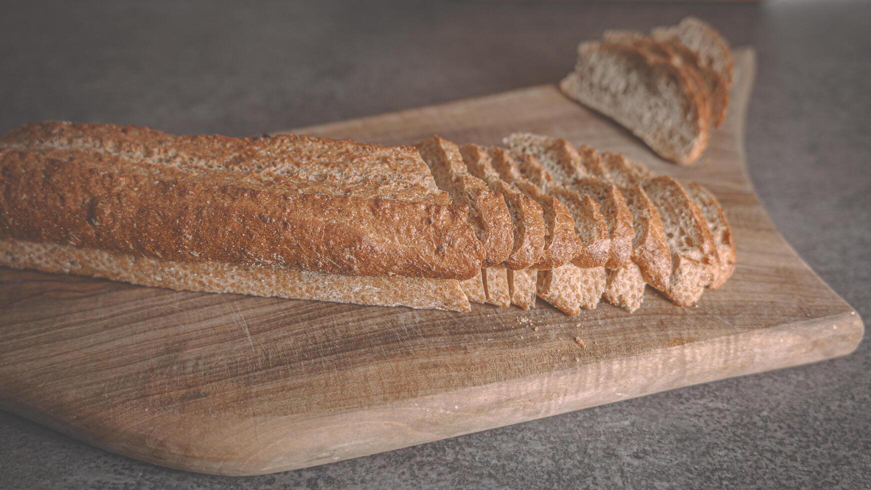 Baguette of dark buckwheat bread on a wooden cutting board. Close-up photo