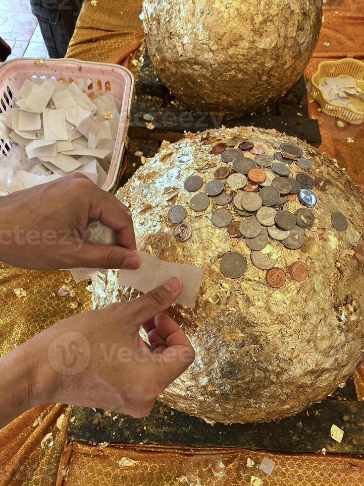 put gold leaf onto stone ball to gild at temple in Thailand, chiang rai, 13 may 2024. photo
