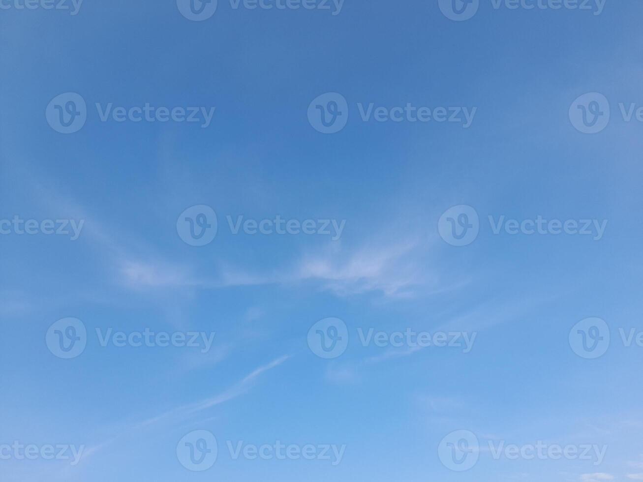 White clouds in the blue sky. Beautiful bright blue background. Light cloudy, good weather. Curly clouds on a sunny day. photo
