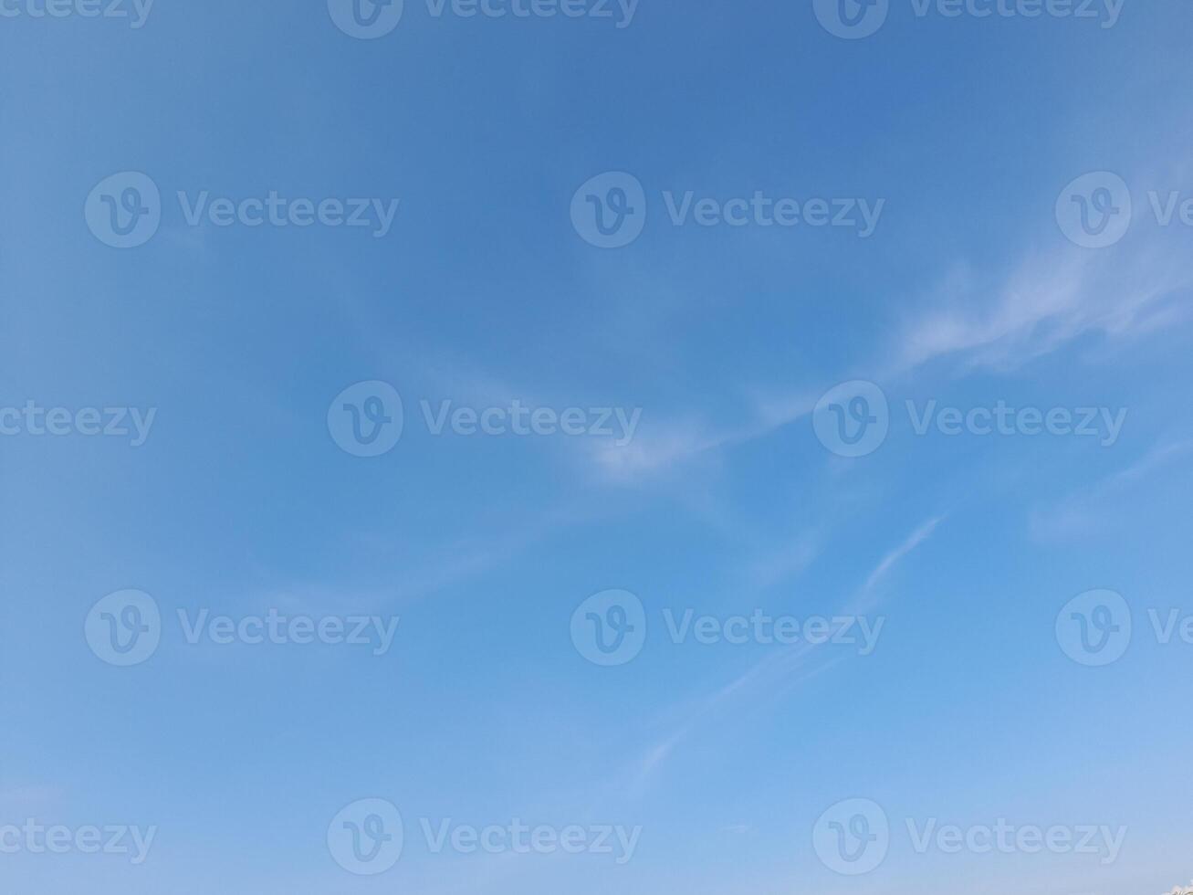 White clouds in the blue sky. Beautiful bright blue background. Light cloudy, good weather. Curly clouds on a sunny day. photo