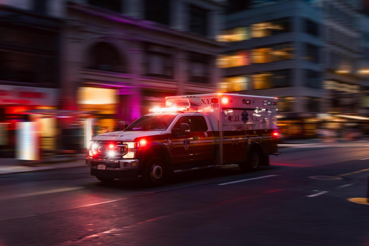 New York, US - May 8, 2023 - Ambulance flashing lights siren blasting speed through midtown rush hour traffic in Manhattan. Motion blur. photo