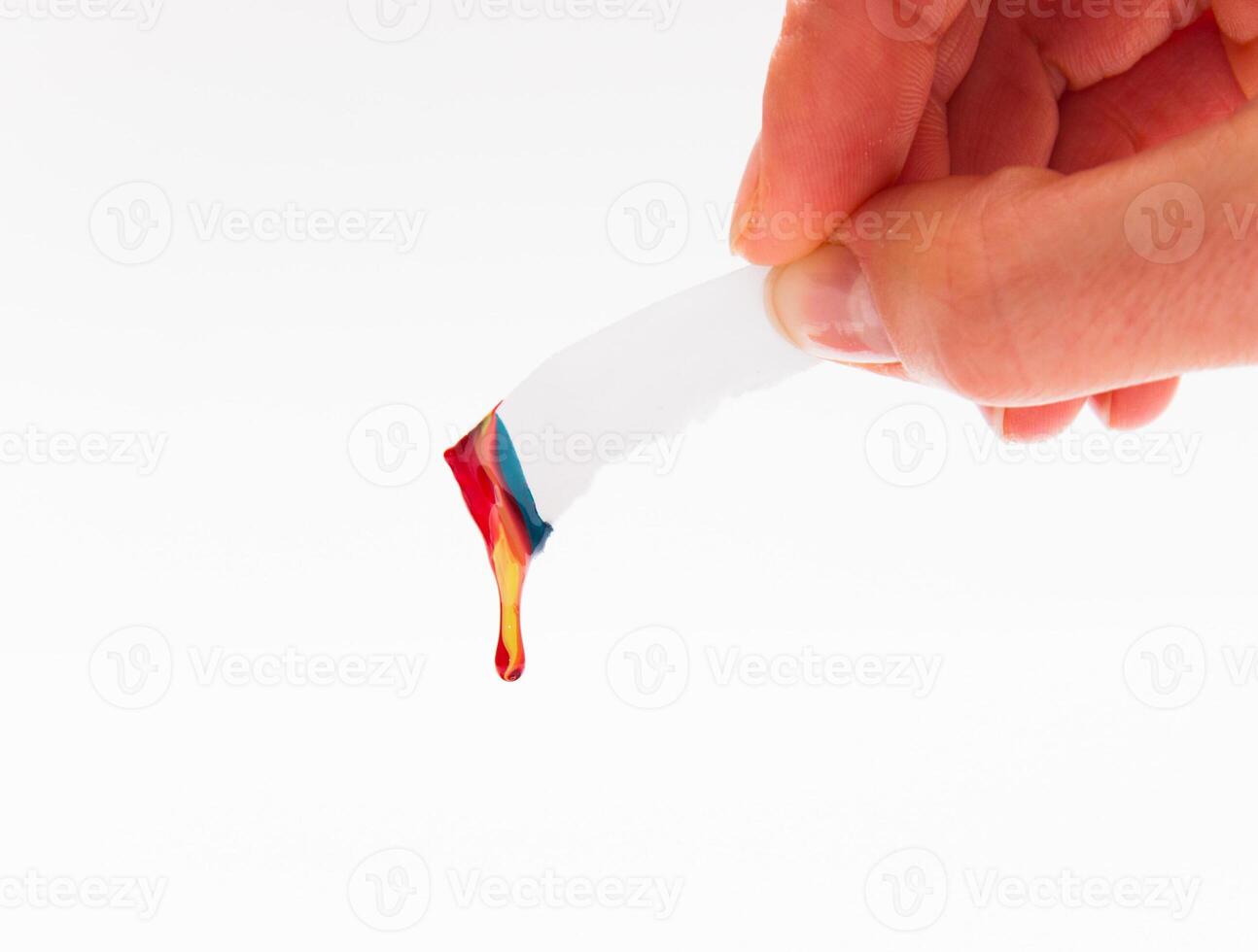 Peace of a paper with a drop of paint, in the hand photo