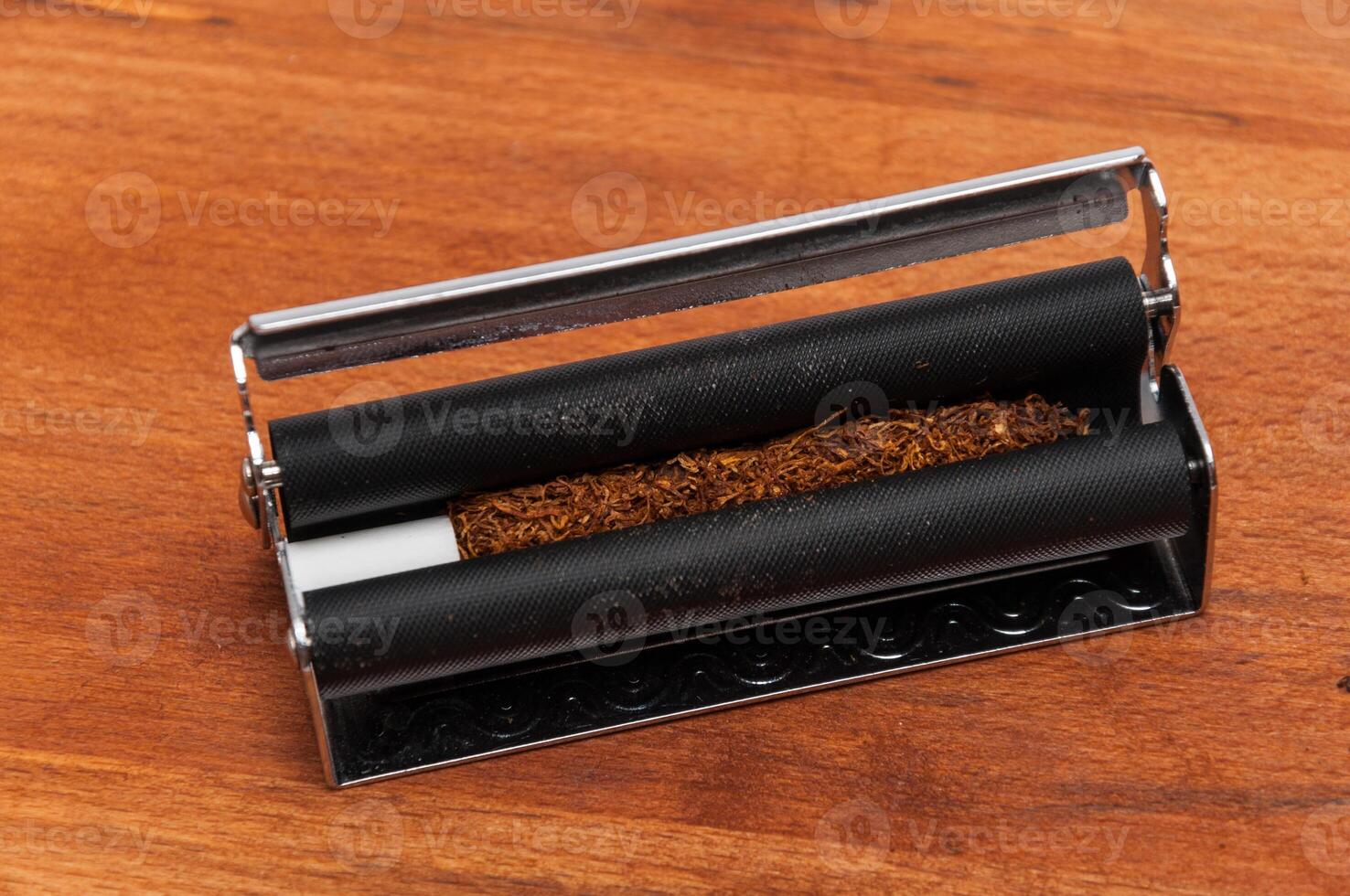 Hand rolling tobacco with the filter in the machine photo