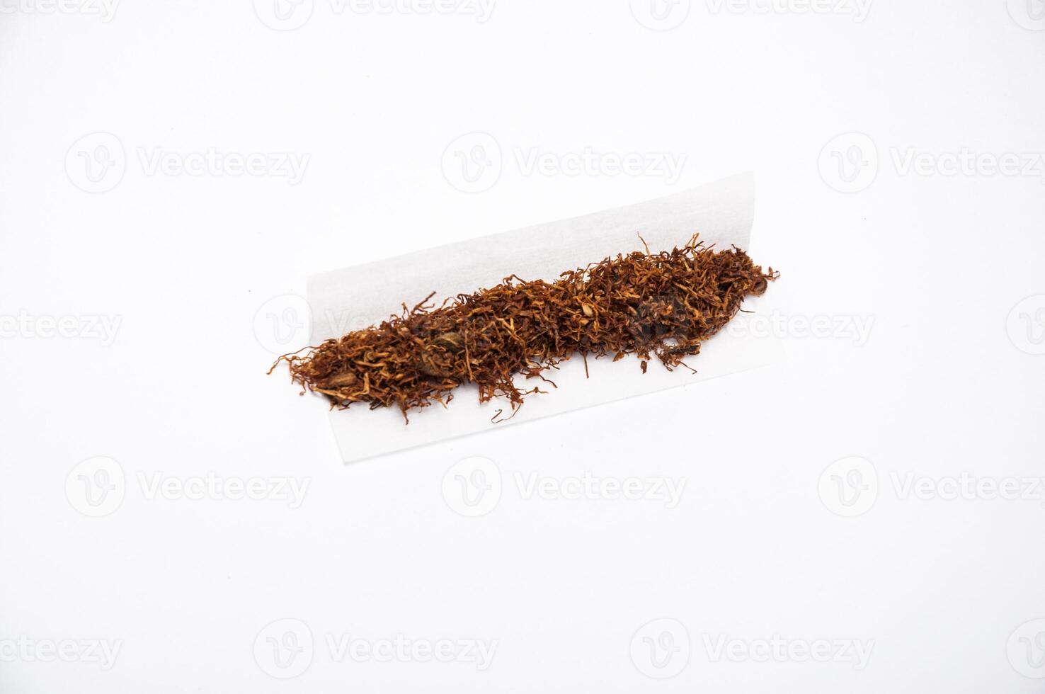 Close up shot of hand rolling tobacco on the white background in paper photo