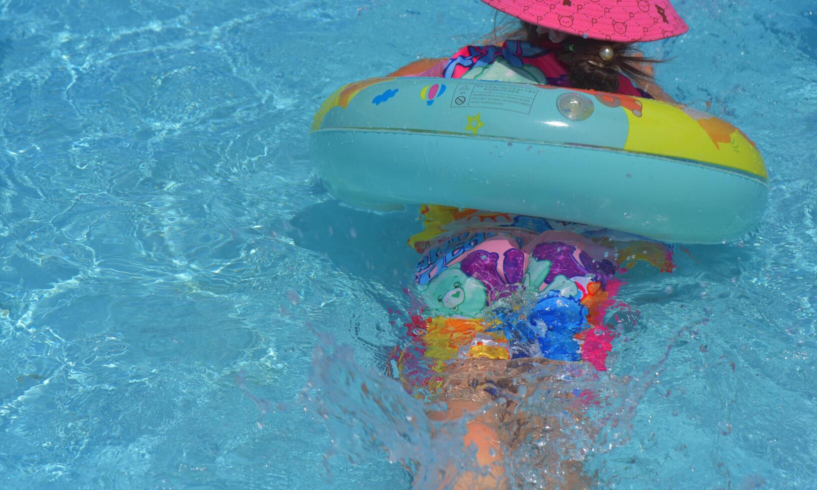 Child in the swimming pool. children playing in the pool. children playing on the beach, or swimming pool on a hot summer day. Kids learn to swim. Child water toys. Children play in tropical resorts. photo