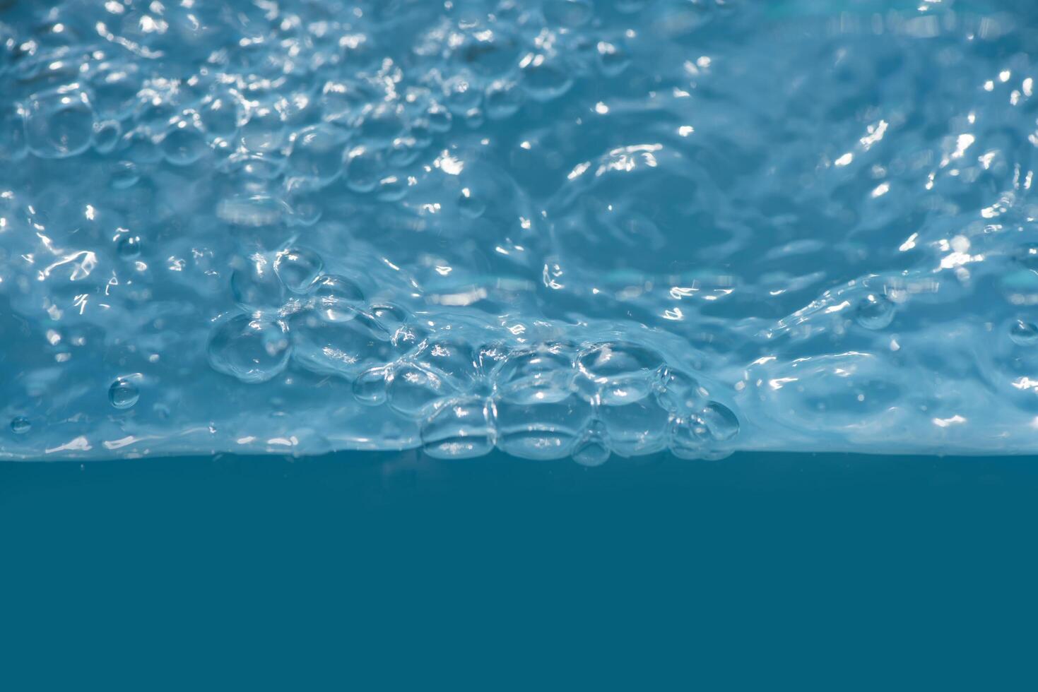 Bluewater waves on the surface ripples blurred. Defocus blurred transparent blue colored clear calm water surface texture with splash and bubbles. Water waves with shining pattern texture background. photo
