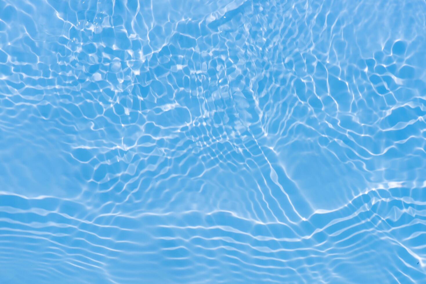 Blue water with ripples on the surface. Defocus blurred transparent blue colored clear calm water surface texture with splashes and bubbles. Water waves with shining pattern texture background. photo