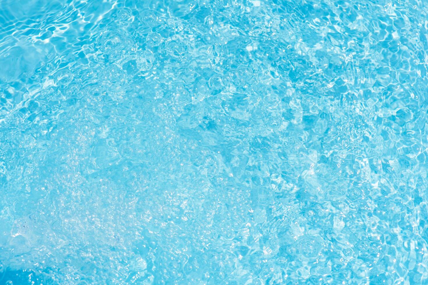 Bluewater waves on the surface ripples blurred. Defocus blurred transparent blue colored clear calm water surface texture with splash and bubbles. Water waves with shining pattern texture background. photo