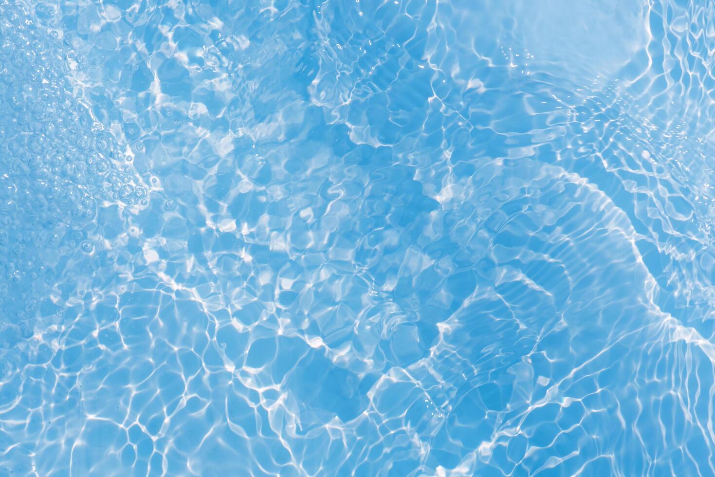 Blue water with ripples on the surface. Defocus blurred transparent blue colored clear calm water surface texture with splashes and bubbles. Water waves with shining pattern texture background. photo