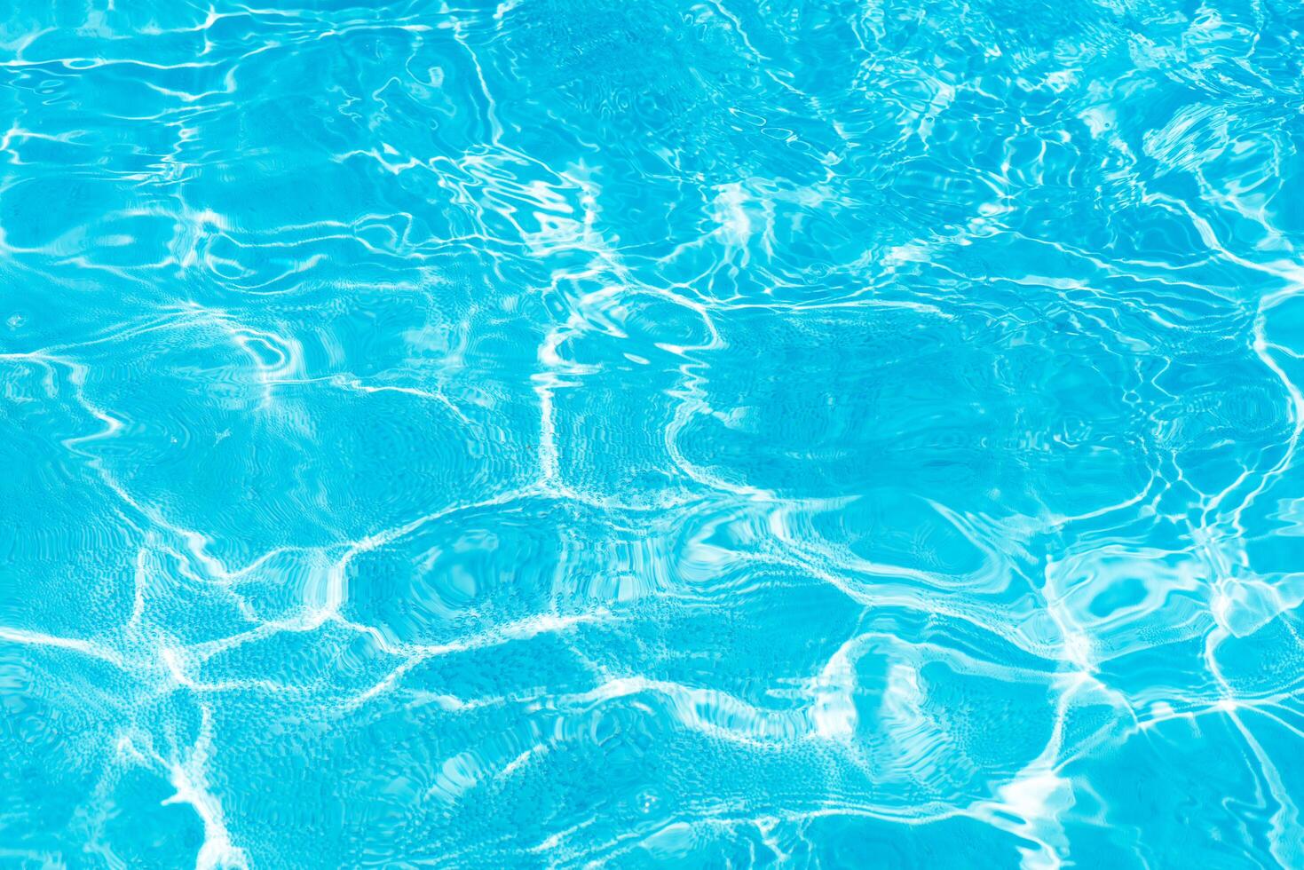 Blue water with ripples on the surface. Defocus blurred transparent blue colored clear calm water surface texture with splashes and bubbles. Water waves with shining pattern texture background. photo