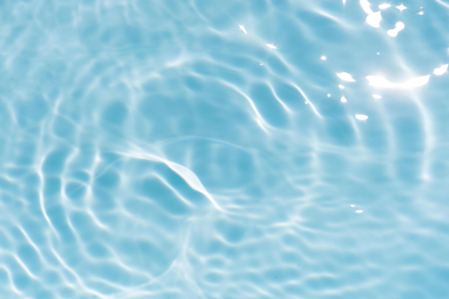 Blue water with ripples on the surface. Defocus blurred transparent blue colored clear calm water surface texture with splashes and bubbles. Water waves with shining pattern texture background. photo