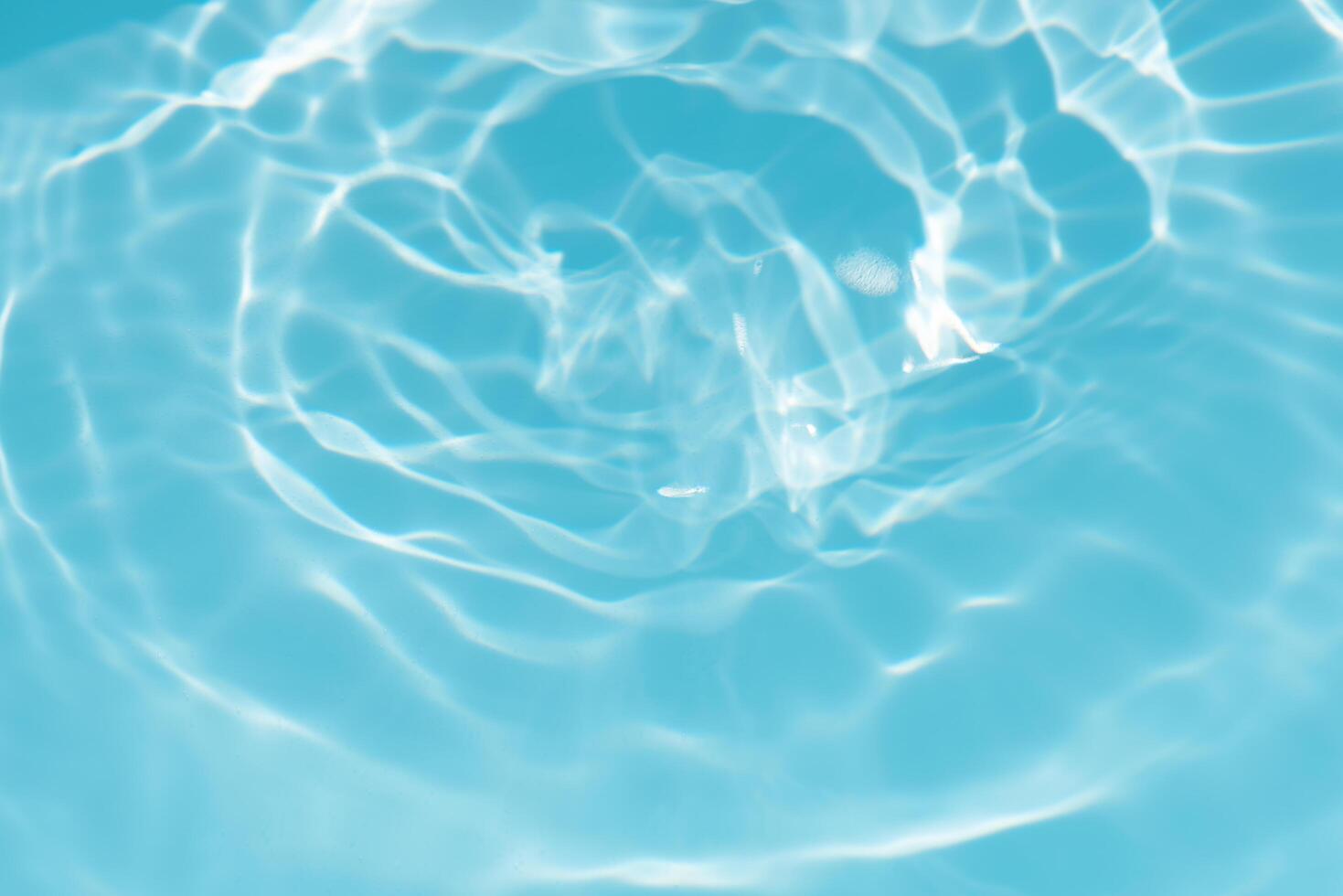 Blue water with ripples on the surface. Defocus blurred transparent blue colored clear calm water surface texture with splashes and bubbles. Water waves with shining pattern texture background. photo