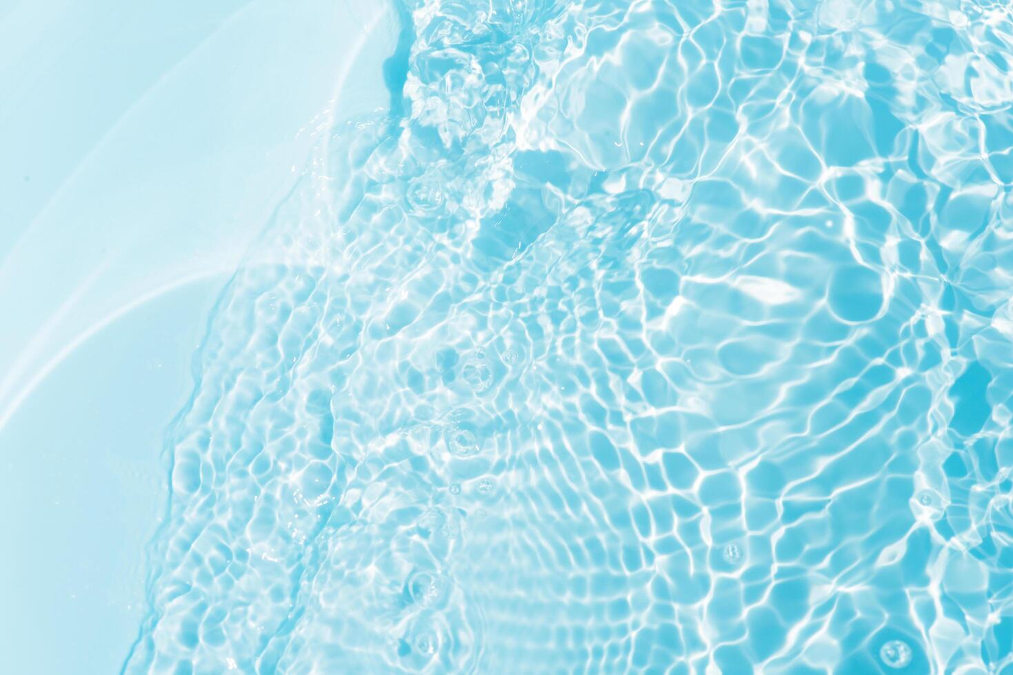 Blue water with ripples on the surface. Defocus blurred transparent blue colored clear calm water surface texture with splashes and bubbles. Water waves with shining pattern texture background. photo