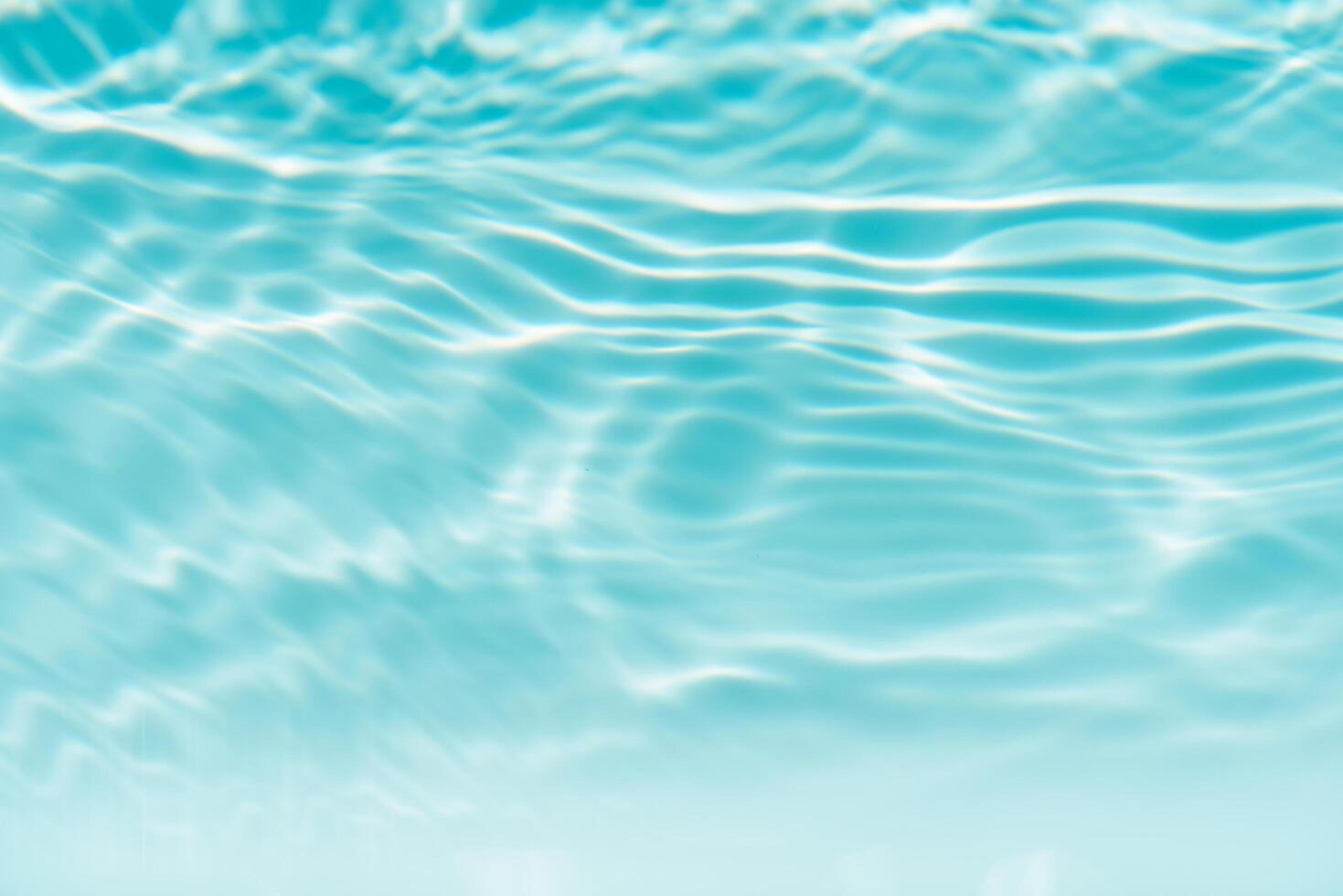 Blue water with ripples on the surface. Defocus blurred transparent blue colored clear calm water surface texture with splashes and bubbles. Water waves with shining pattern texture background. photo