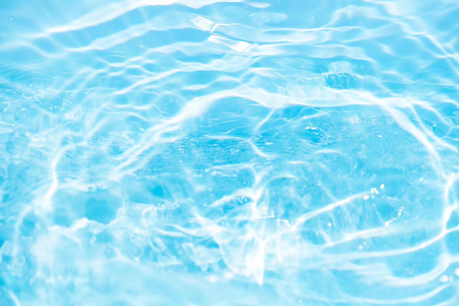 Blue water with ripples on the surface. Defocus blurred transparent blue colored clear calm water surface texture with splashes and bubbles. Water waves with shining pattern texture background. photo