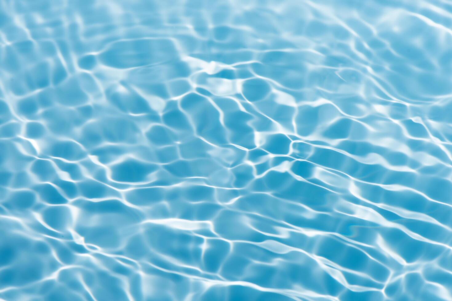 Blue water with ripples on the surface. Defocus blurred transparent blue colored clear calm water surface texture with splashes and bubbles. Water waves with shining pattern texture background. photo