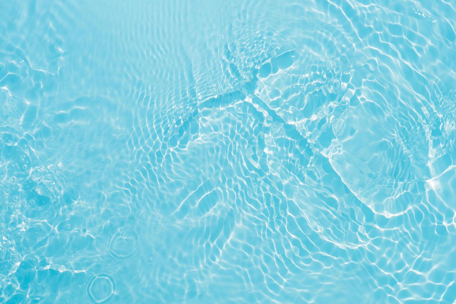 Blue water with ripples on the surface. Defocus blurred transparent blue colored clear calm water surface texture with splashes and bubbles. Water waves with shining pattern texture background. photo