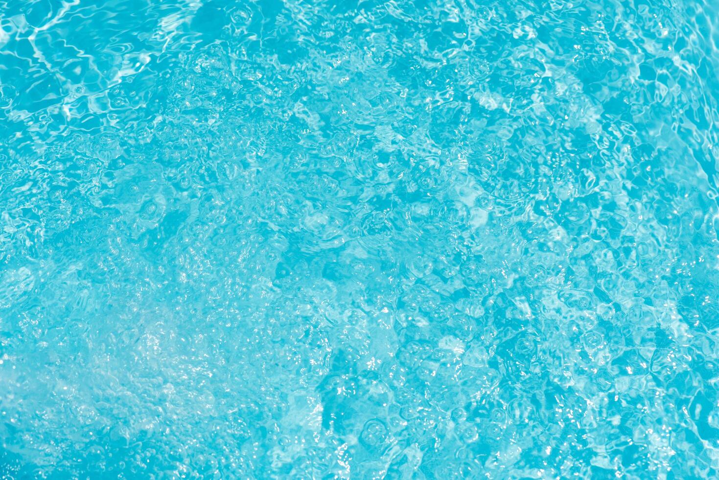 Blue water with ripples on the surface. Defocus blurred transparent blue colored clear calm water surface texture with splashes and bubbles. Water waves with shining pattern texture background. photo