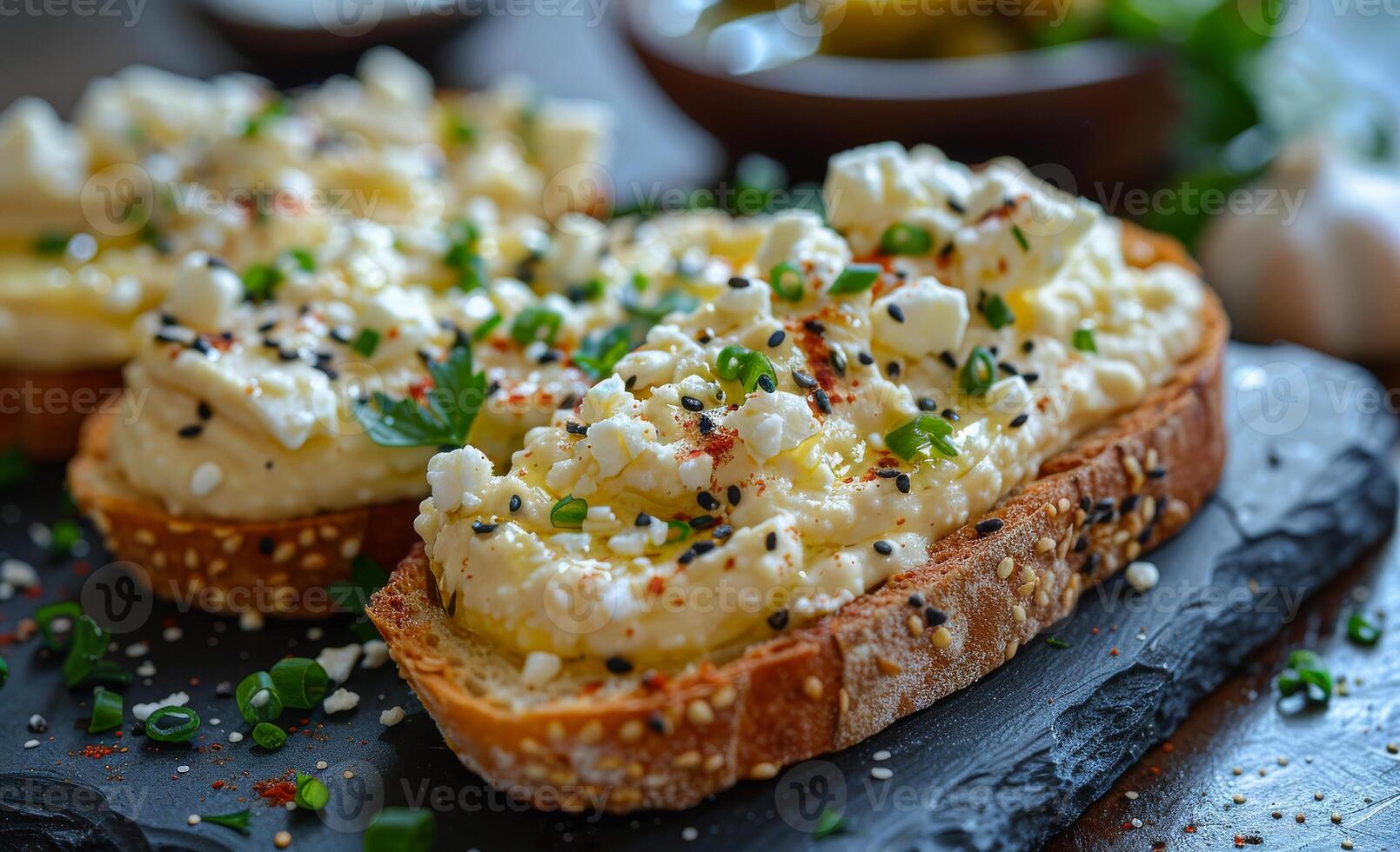 Two slices of bread with a creamy white spread and black sesame seeds on top photo