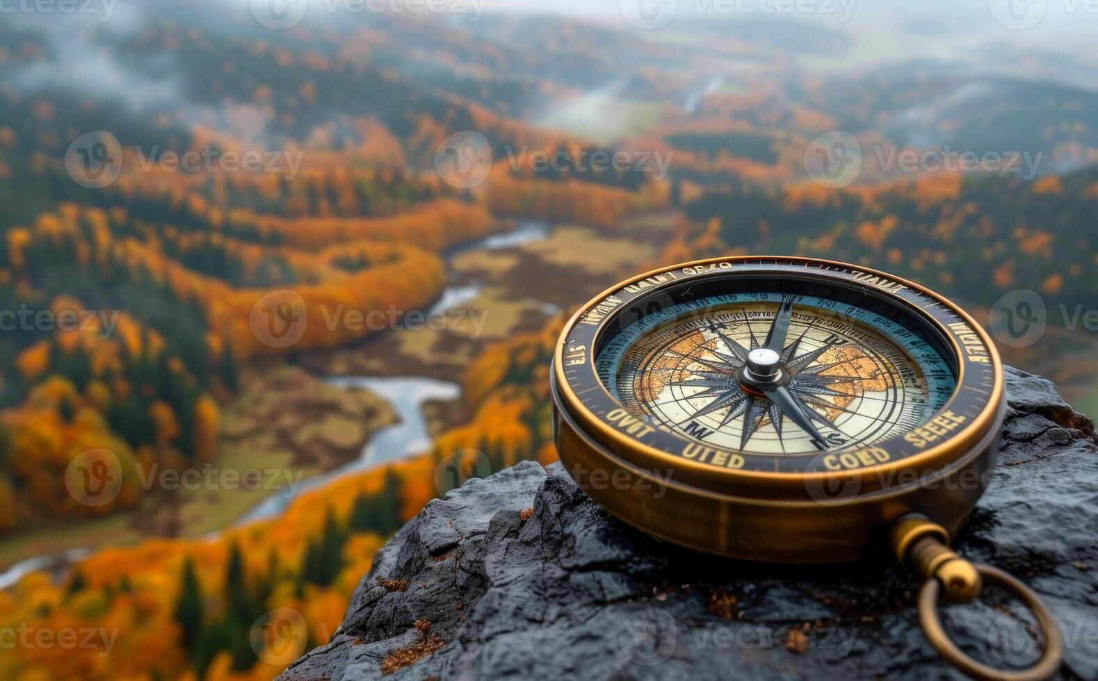 Compass sits on rock overlooking river and forest photo