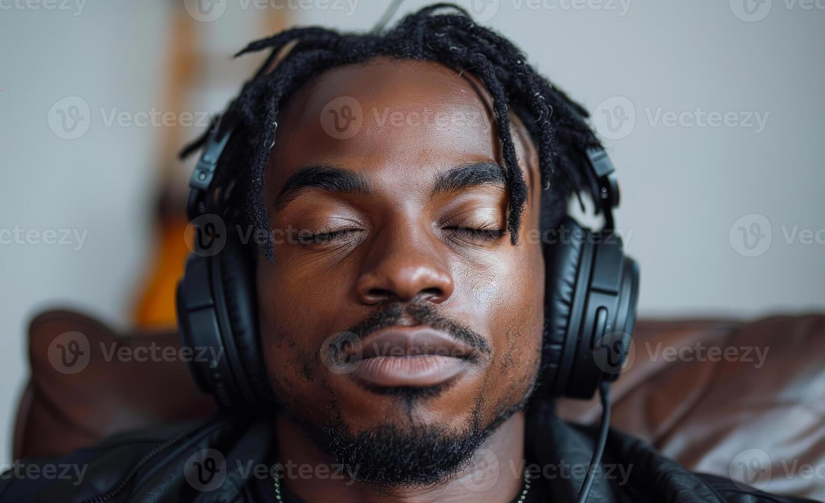 Man sits on couch with headphones on eyes closed and his eyes closed. photo