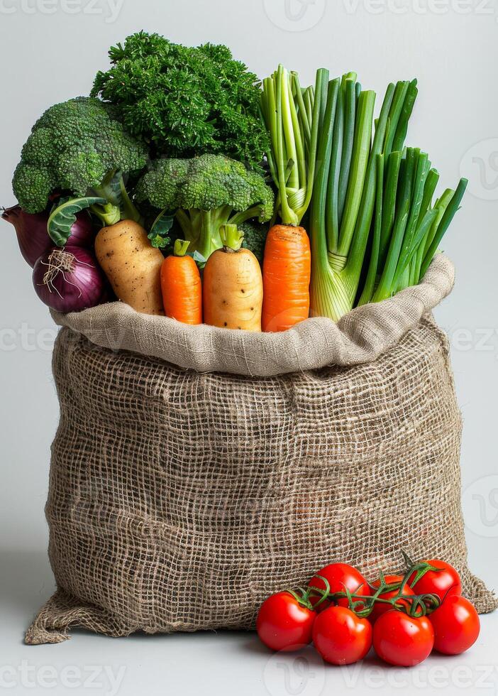Burlap sack filled with fresh vegetables on white background photo