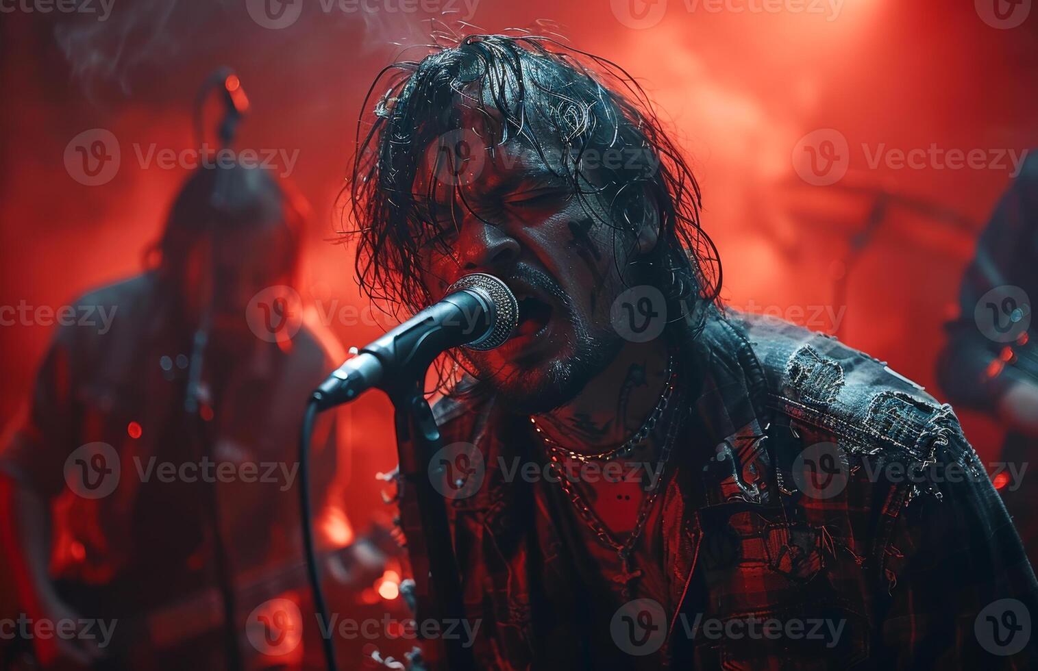 Heavy metal singer screaming into the microphone while performing on stage with his band. photo
