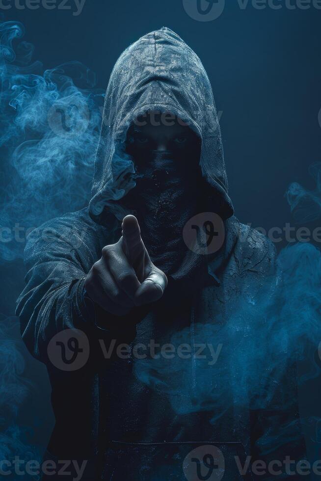 Mysterious man in hood pointing the finger in the camera in the dark photo