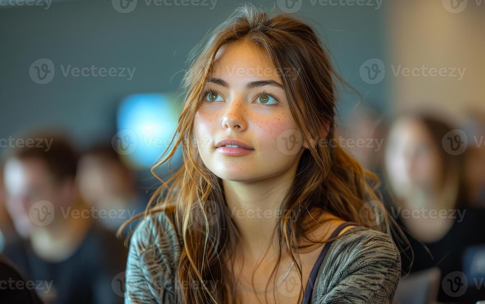 Young woman looks up while sitting in lecture hall. A female university student in a seminar photo