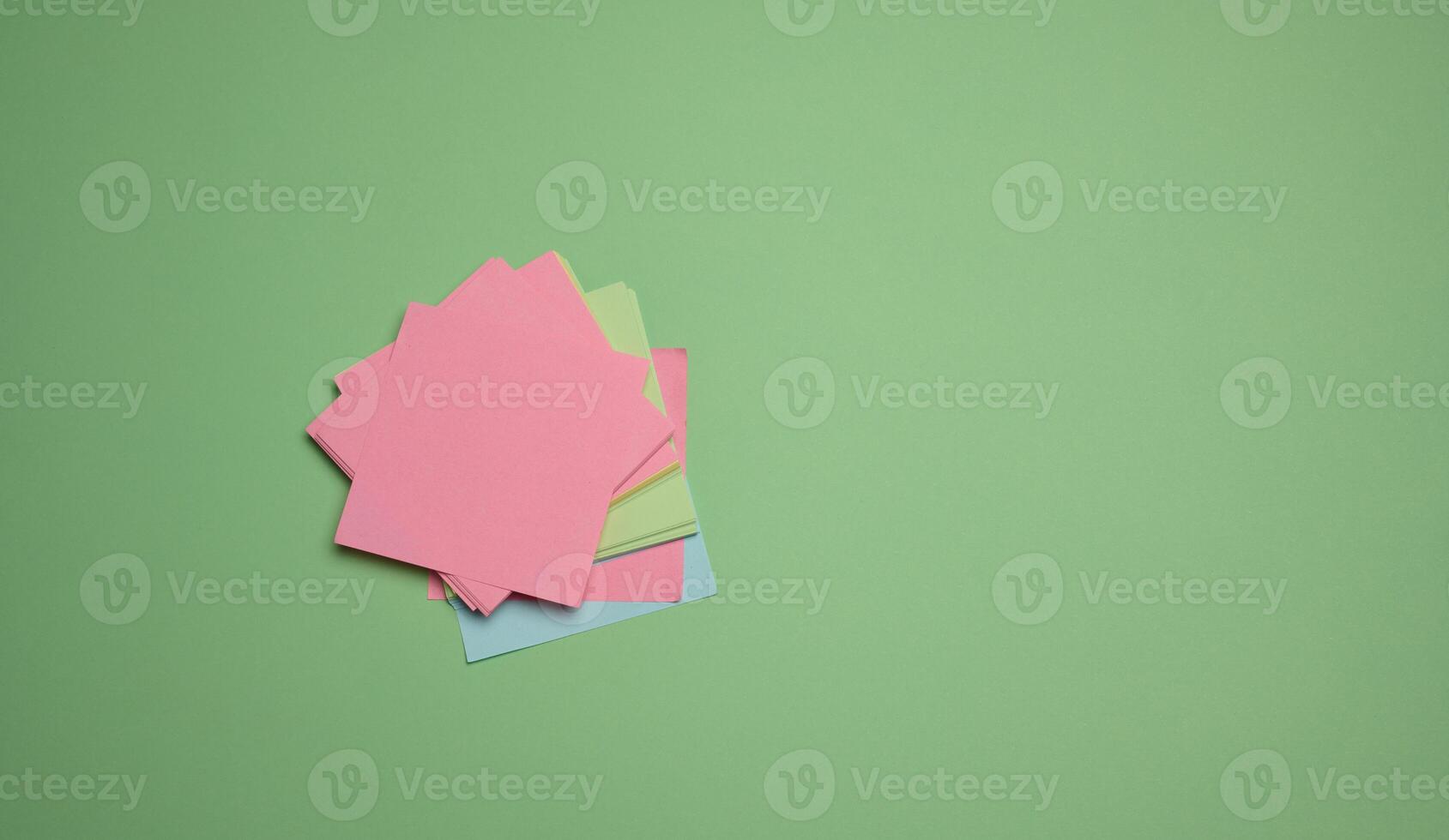 Stack of paper blank stickers on green background, top view photo