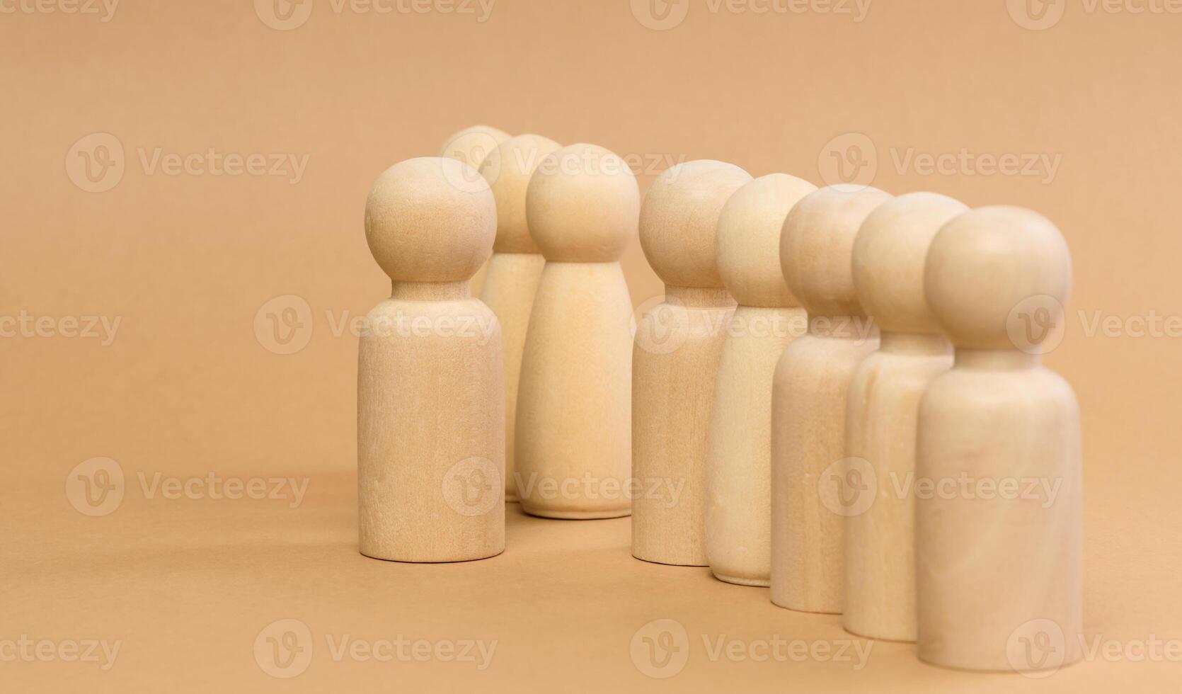 A row of wooden figures and one standing in front. Recruitment concept photo