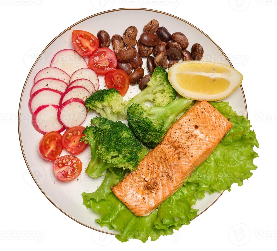 Healthy lunch with grilled trout on green lettuce, next to vegetables, tomatoes, radishes, broccoli and a portion of beans photo