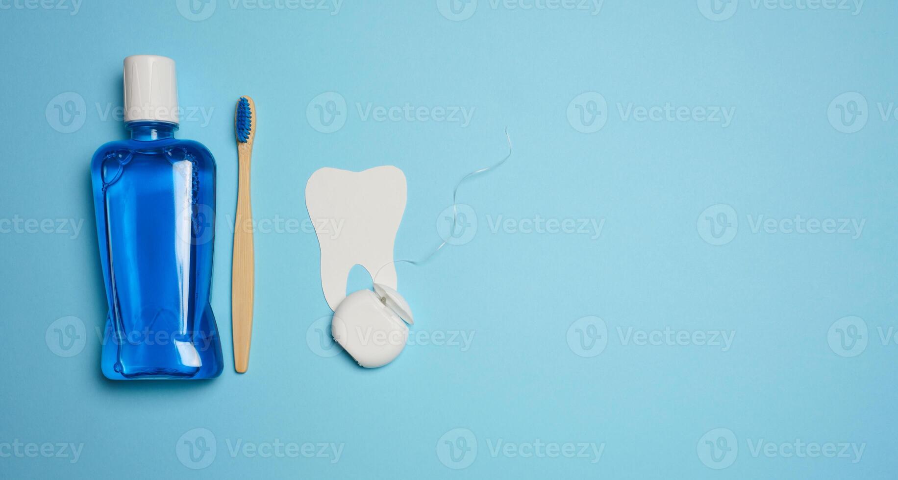 Plastic bottle with mouthwash, wooden toothbrush on blue background photo