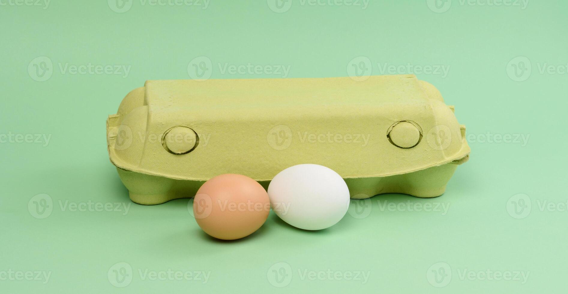 Two chicken eggs in a paper box on a green background photo