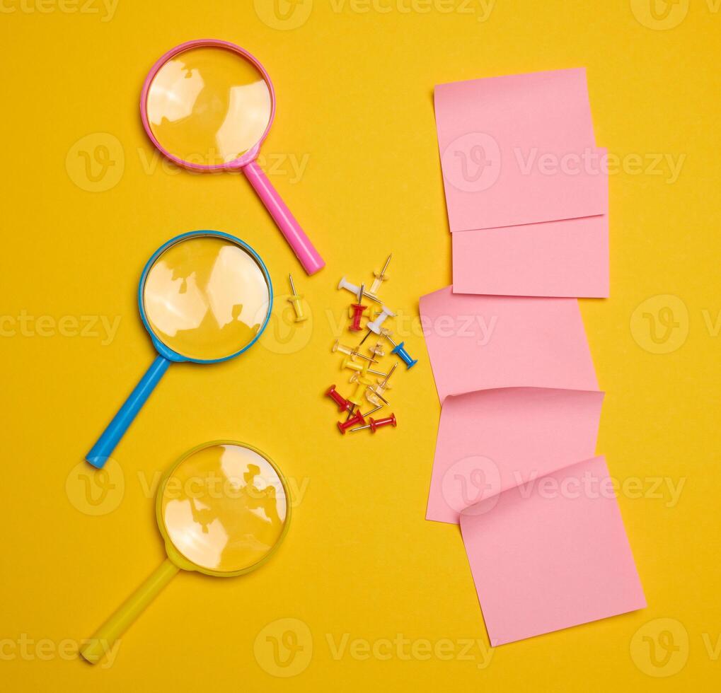 Plastic magnifying glass and empty paper stickers on yellow background photo