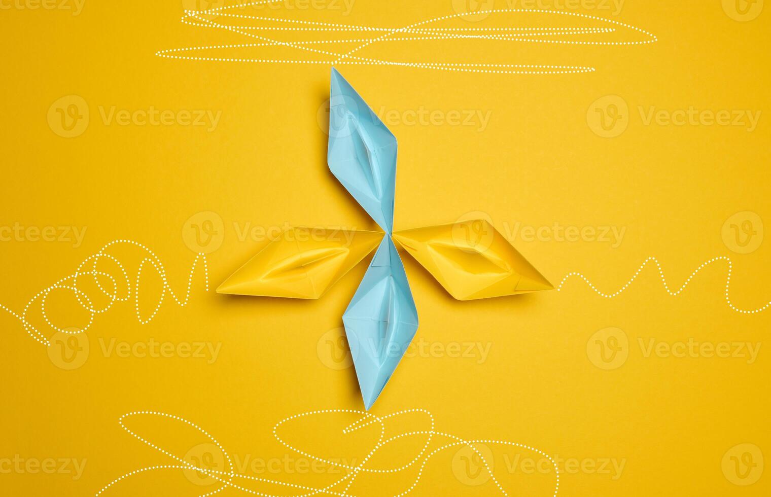 Four paper boats stand at the same departure point, but different trajectories are drawn. The concept of uniqueness photo