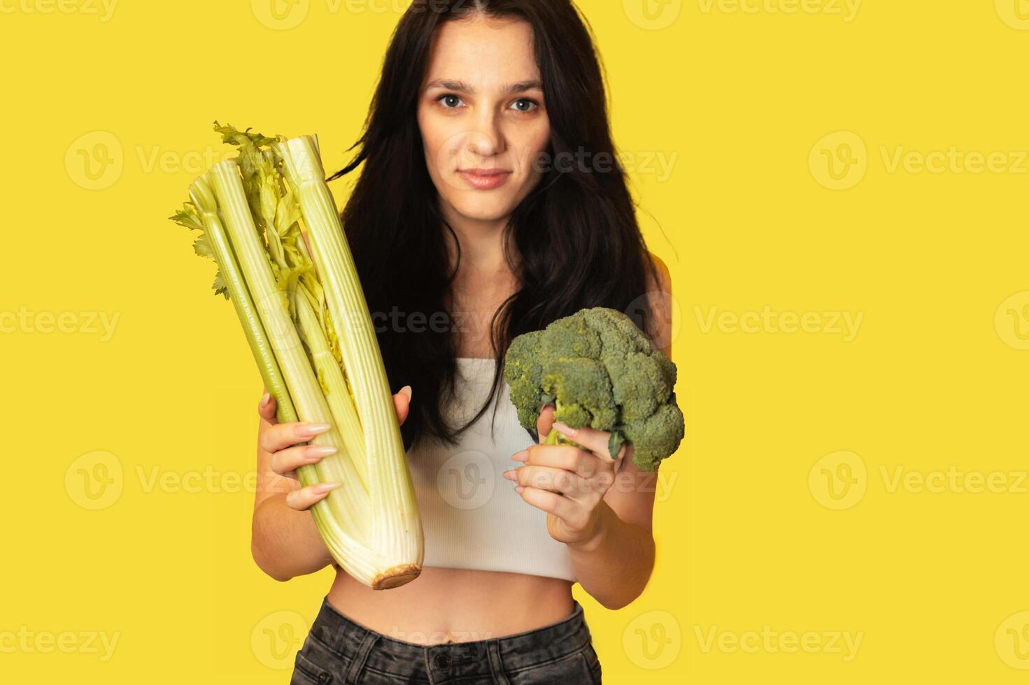 Smiling slender Caucasian girl with green vegetables in her hands, broccoli and celery. Organic vegetables. photo