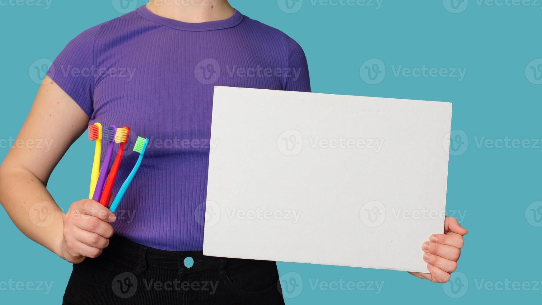 A close-up of a set of colorful toothbrushes and a blank sheet in women's hands to write text on it. Panoramic banner photo
